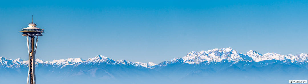 The Seattle Space Needle singled out with the snow-capped Olympic Mountains behind on a blue sky day