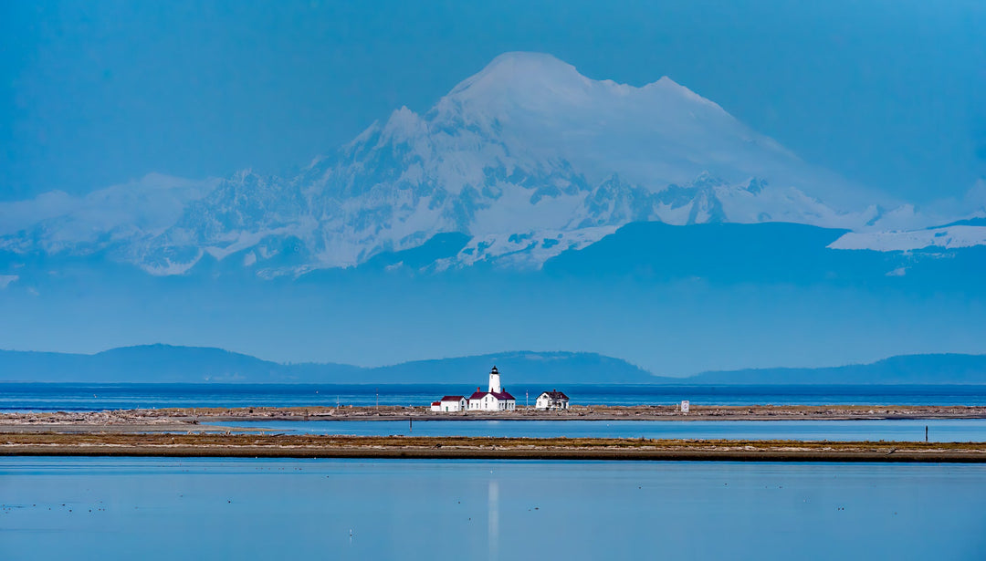 The new Dungeness Spit Lighthouse in the foreground and the massive volcano, Mt. Baker, looming in the background over the foothills.